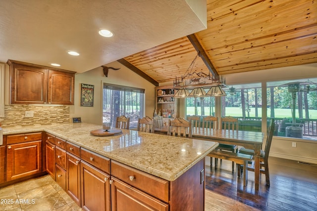 kitchen featuring tasteful backsplash, lofted ceiling, a wealth of natural light, and a peninsula