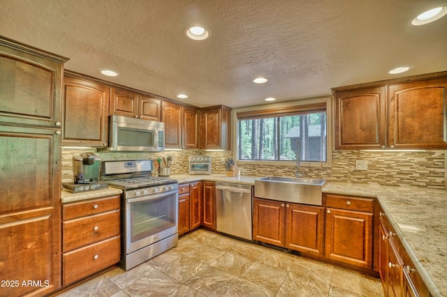 kitchen with brown cabinetry, appliances with stainless steel finishes, backsplash, and a sink