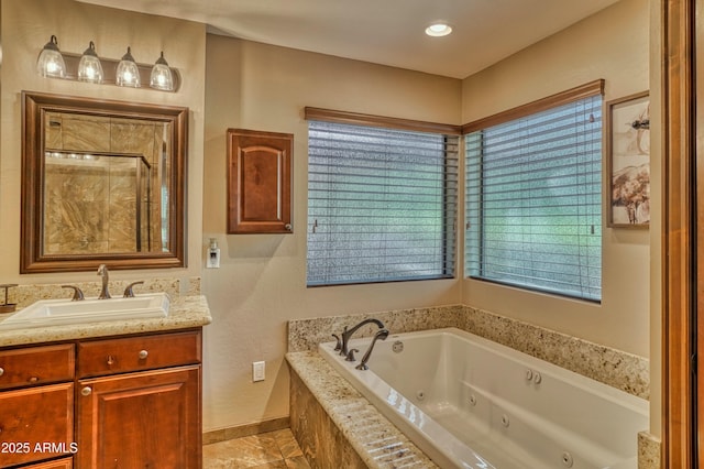 bathroom with baseboards, a tile shower, a jetted tub, and vanity