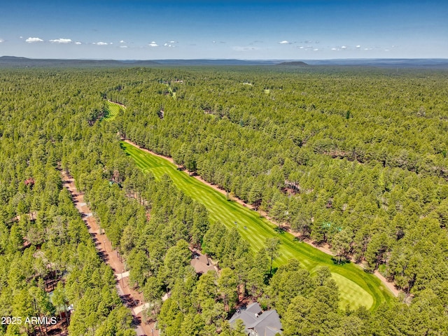 drone / aerial view with golf course view and a wooded view