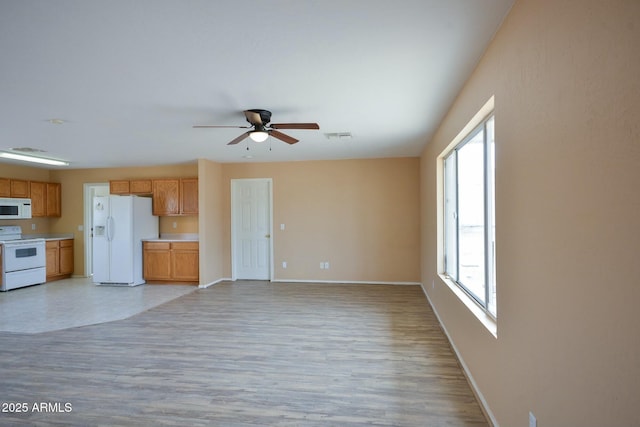 kitchen with white appliances, baseboards, light countertops, and open floor plan