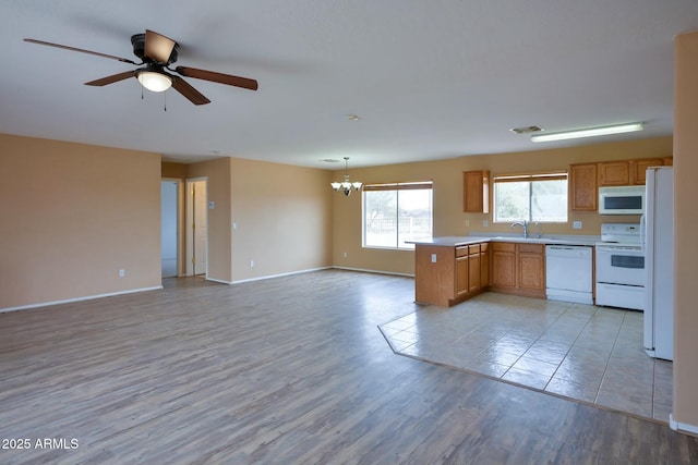 kitchen with light wood-type flooring, white appliances, open floor plan, and a sink