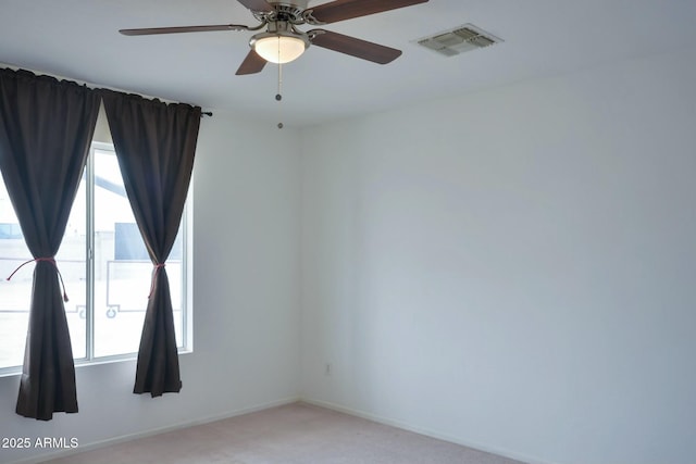 spare room featuring a ceiling fan, light colored carpet, visible vents, and baseboards