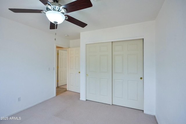 unfurnished bedroom featuring baseboards, ceiling fan, a closet, and light colored carpet