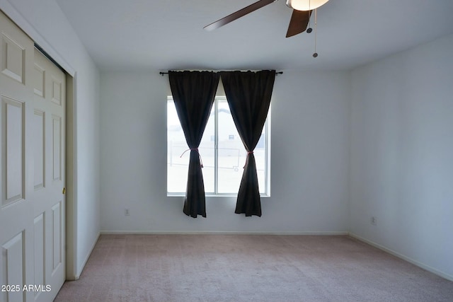 unfurnished room with a ceiling fan, light carpet, and baseboards