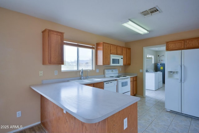 kitchen with white appliances, a sink, visible vents, light countertops, and washer and clothes dryer