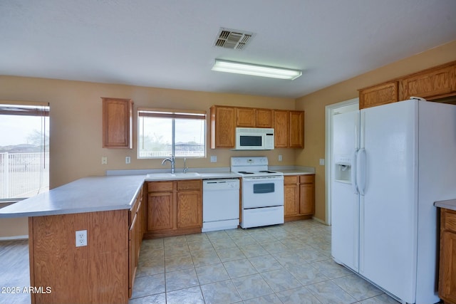 kitchen featuring white appliances, visible vents, a peninsula, light countertops, and a sink