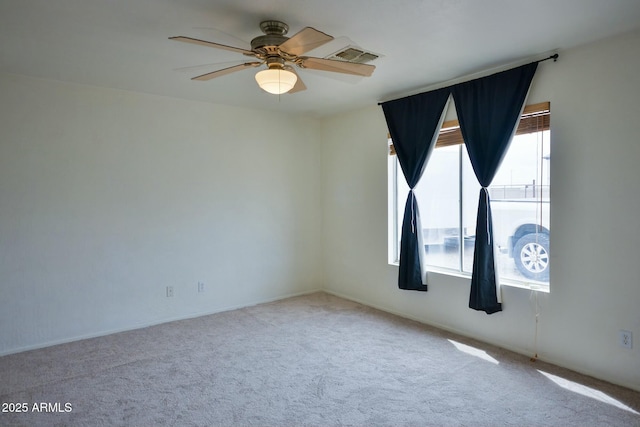 carpeted spare room with visible vents and a ceiling fan