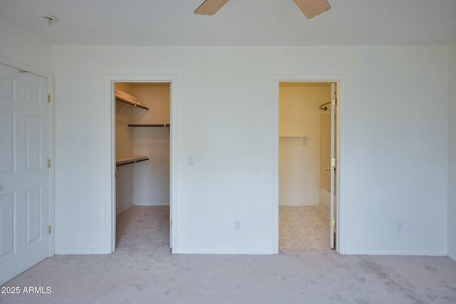 unfurnished bedroom featuring carpet floors, a walk in closet, a closet, and ceiling fan