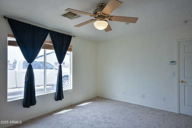 carpeted empty room with ceiling fan and visible vents