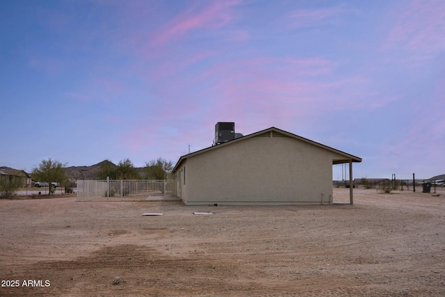 view of home's exterior featuring stucco siding, fence, and central air condition unit