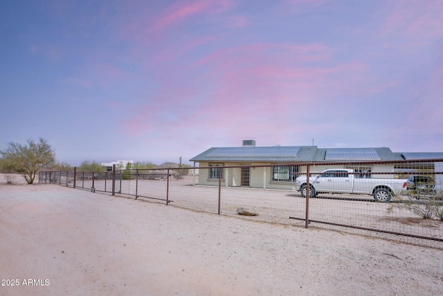 view of front of property featuring roof mounted solar panels and fence