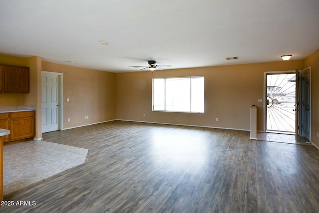 unfurnished living room featuring a ceiling fan, wood finished floors, visible vents, and baseboards