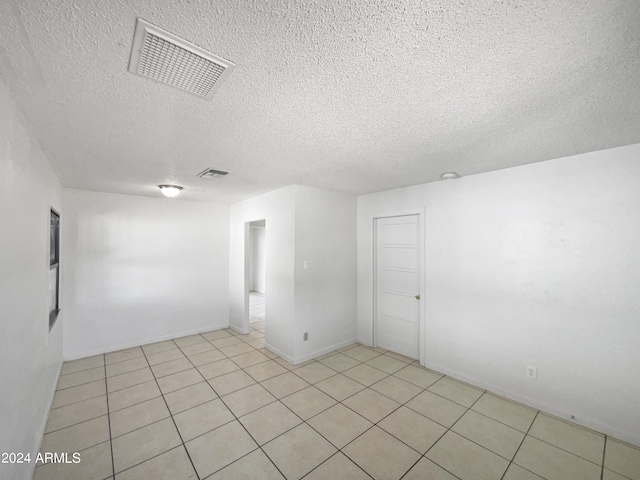 empty room featuring a textured ceiling and light tile patterned floors