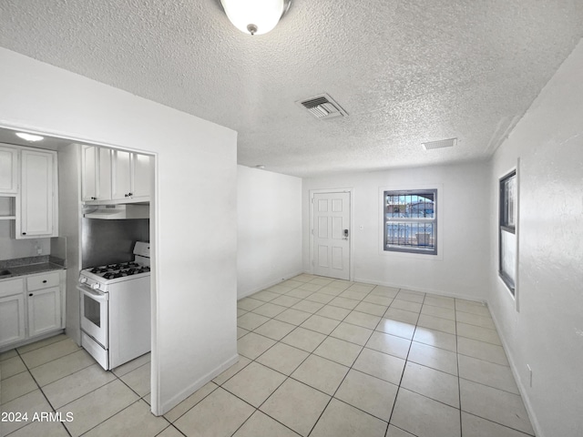 kitchen featuring white cabinetry, white range with gas cooktop, light tile patterned flooring, and a textured ceiling