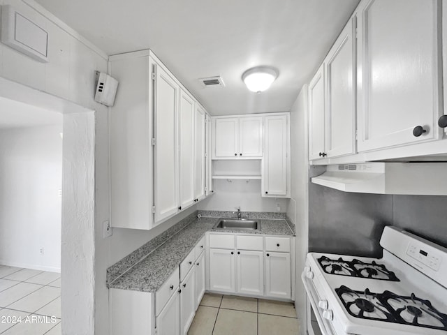 kitchen with white cabinetry, sink, white gas range oven, and light tile patterned floors