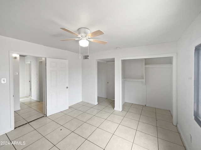 unfurnished bedroom with light tile patterned floors, ceiling fan, and a closet