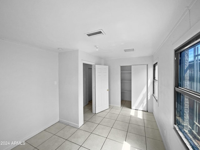 unfurnished bedroom with multiple windows, light tile patterned floors, and a closet