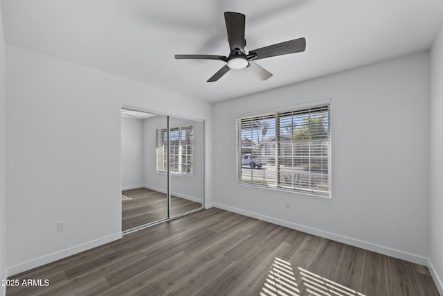 unfurnished bedroom featuring ceiling fan, a closet, and dark wood-type flooring