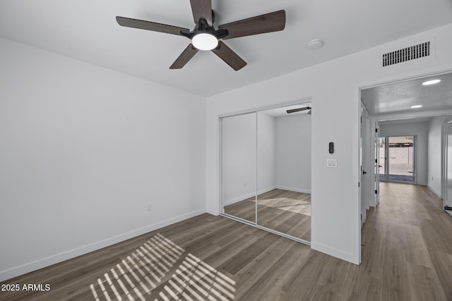 unfurnished bedroom featuring ceiling fan, hardwood / wood-style floors, and a closet