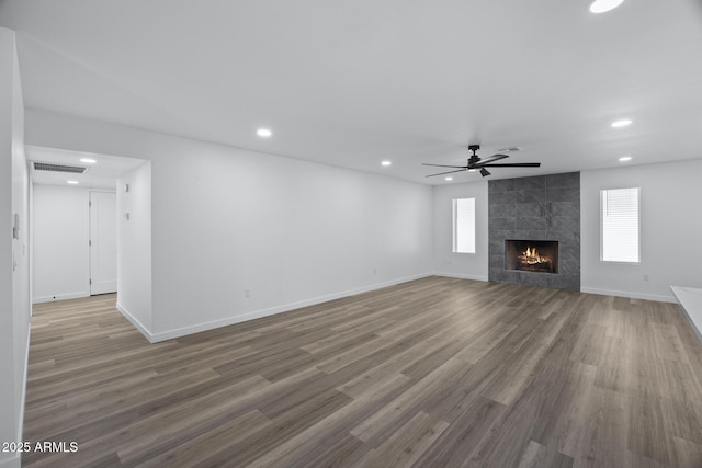 unfurnished living room with hardwood / wood-style flooring, ceiling fan, and a fireplace