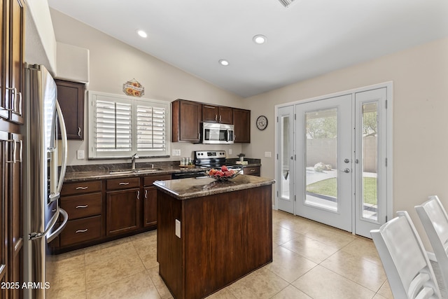 kitchen with stainless steel appliances, a sink, vaulted ceiling, a kitchen island, and dark brown cabinets