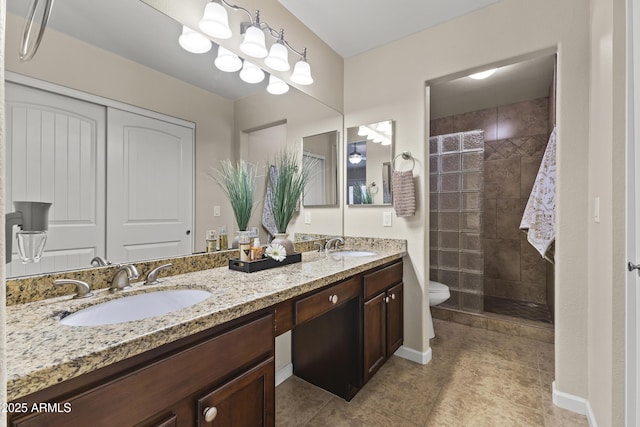 full bath featuring a tile shower, toilet, double vanity, and tile patterned floors