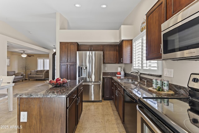 kitchen with stainless steel appliances, a sink, a kitchen island, dark stone countertops, and recessed lighting