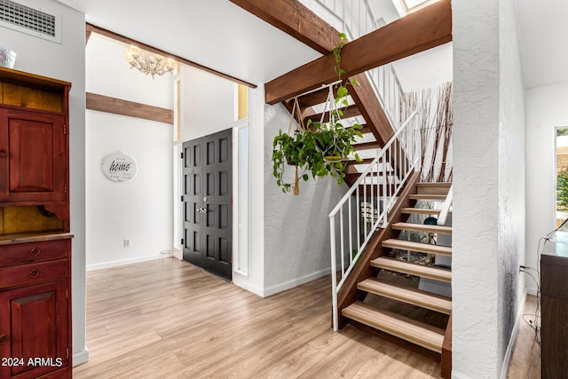 foyer featuring beam ceiling and light wood-type flooring