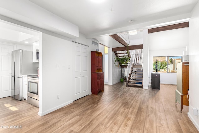 interior space featuring lofted ceiling with beams and light hardwood / wood-style floors