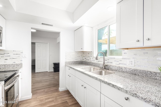 kitchen featuring electric stove, sink, light hardwood / wood-style floors, light stone countertops, and white cabinets