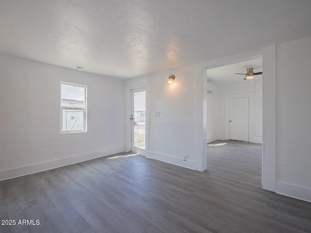 spare room with dark wood-style flooring, a textured ceiling, and baseboards