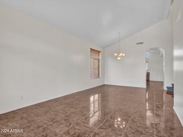 empty room featuring high vaulted ceiling and a chandelier