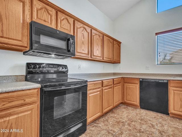 kitchen with black appliances, vaulted ceiling, and light tile patterned floors