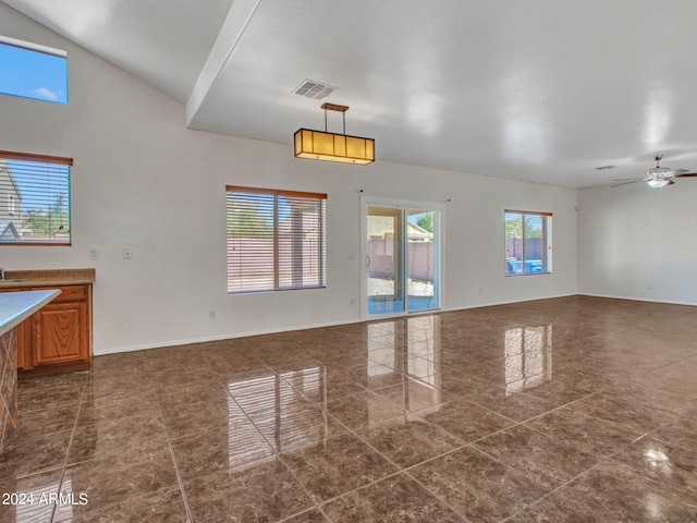 unfurnished living room with lofted ceiling, dark tile patterned flooring, and ceiling fan