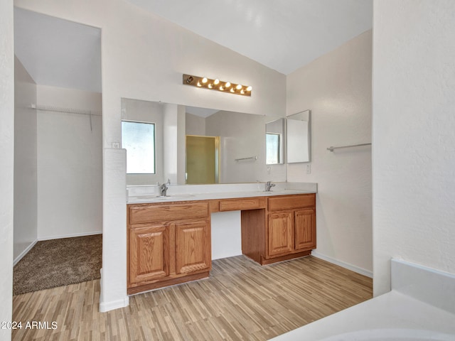 bathroom with vanity, wood-type flooring, vaulted ceiling, and a shower with door