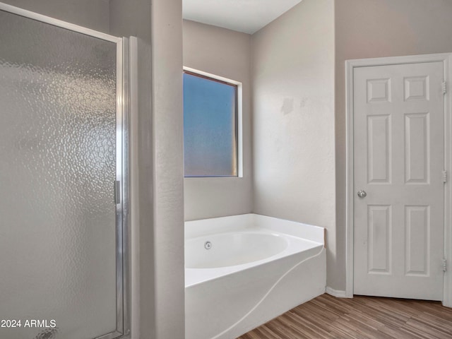 bathroom with shower with separate bathtub and wood-type flooring