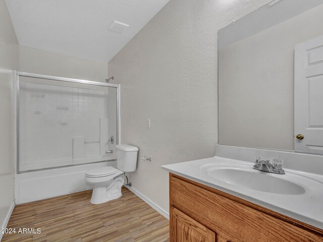 full bathroom with enclosed tub / shower combo, wood-type flooring, vaulted ceiling, toilet, and vanity