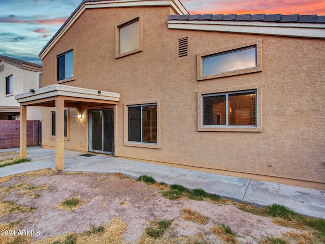 back house at dusk with a patio