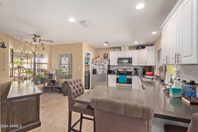 kitchen featuring kitchen peninsula, appliances with stainless steel finishes, ceiling fan, sink, and white cabinets