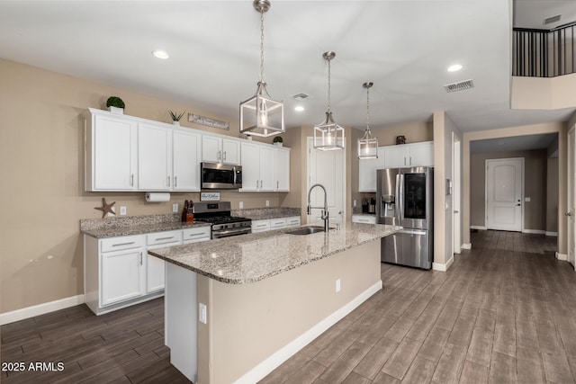 887 W Santa Gertrudis Trl, San Tan Valley, AZ 85143 - kitchen featuring stainless steel appliances, a sink, baseboards, dark wood-type flooring, and a center island with sink