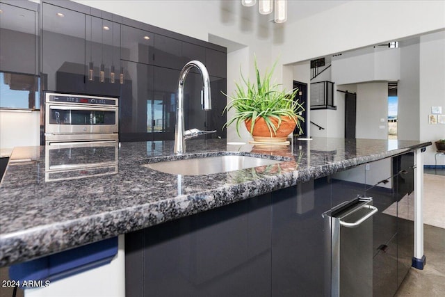 kitchen with dark stone counters, stainless steel double oven, sink, and fridge