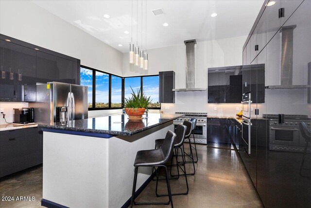 kitchen with decorative light fixtures, a center island, stainless steel appliances, and wall chimney exhaust hood