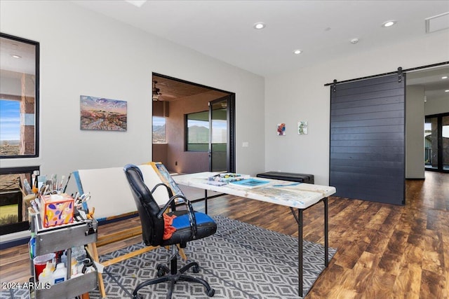 office with dark hardwood / wood-style flooring, ceiling fan, and a barn door