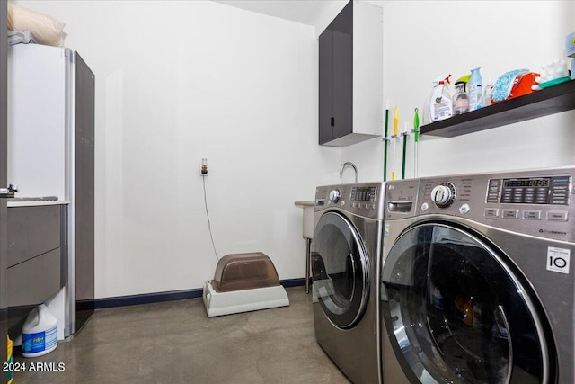 clothes washing area featuring washing machine and dryer and cabinets