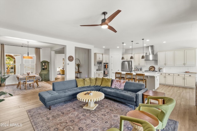 living room featuring ceiling fan, sink, and light hardwood / wood-style floors