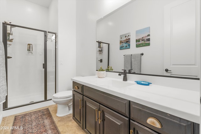 bathroom featuring vanity, toilet, a shower with door, and tile patterned floors