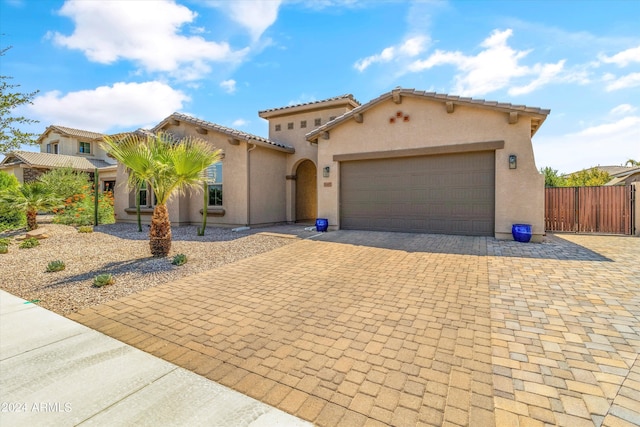 21487 E Arroyo Verde Dr, Queen Creek, AZ 85142 - mediterranean / spanish home with stucco siding, decorative driveway, fence, a tile roof, and an attached garage