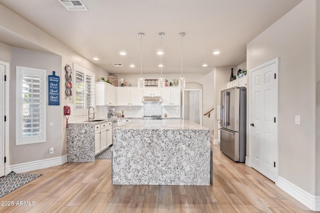 kitchen featuring white cabinets, hanging light fixtures, a kitchen island, sink, and high end fridge