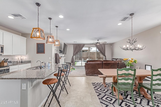 996 W Shannons Way, Coolidge, AZ 85128 - kitchen featuring a sink, a breakfast bar area, ceiling fan, white cabinetry, and light stone countertops